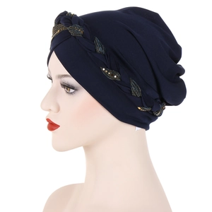 Detail of dark blue turban hat featuring gold sequin leaf braid trim on soft fabric