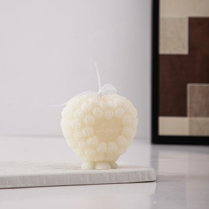 Detail of heart-shaped rose scented candle in creamy white with Love engraving