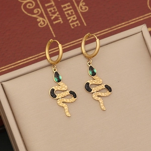 Detailed shot of golden snake earrings with textured scales and gems in a beige gift box