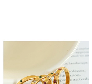 Macro detail of three gold-plated rings with red, green, and white zircon stones
