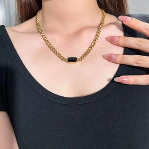 Macro shot of gold Cuban chain necklace with a rectangular black gemstone pendant