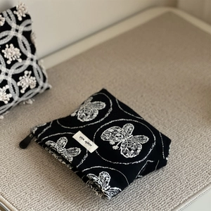 Detail of black cotton canvas pouch with butterfly embroidery and simple wish brand tag