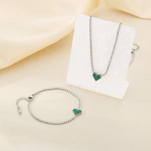 Detail of silver stainless steel heart necklace and bracelet set with green stone inlay