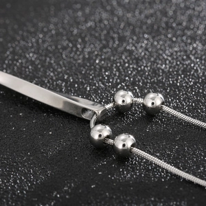 Detailed close-up of a silver stainless steel spiral bar pendant on a snake chain