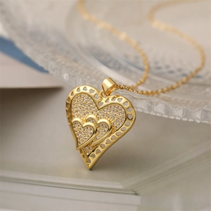 Gold-plated layered heart pendant necklace with cubic zirconia on open book background