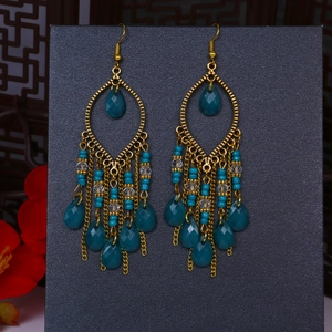Dettaglio orecchini pendenti boho con perline blu lago e nappe metalliche dorate