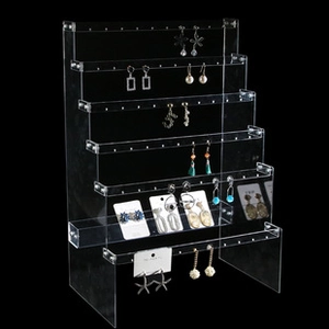 Macro side view of clear six-tier acrylic earring display stand on black background