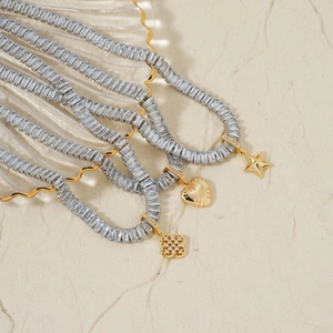 French vintage gold necklaces with star heart and clover pendants on stone surface