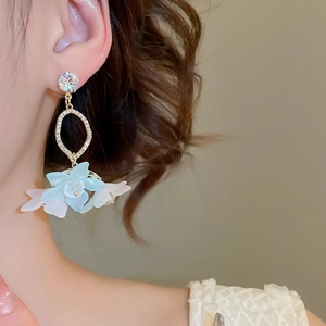 Close-up of floral pendant earrings with blue resin petals on an elegant female model