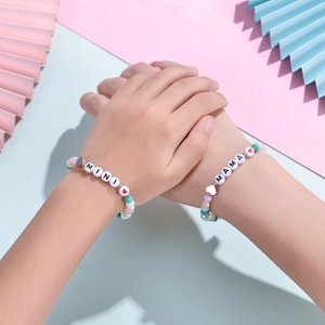 Bracelet perles colorées maman et fille avec breloques MAMA et MINI sur fond rose