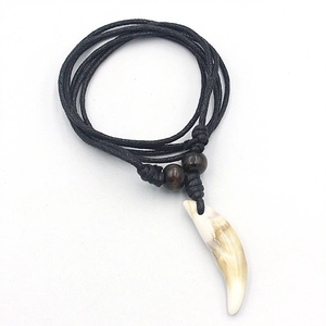 Faux wolf tooth pendant necklace with brown beads and black braided rope on white background