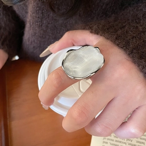 Detail of silver wavy resin ring with white glossy stone worn by model holding a cup