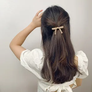 Elegant gold bow hair clip with rhinestones worn on long wavy hair in a half-up style