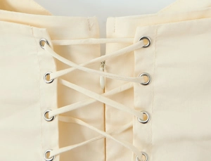 Close-up of cream off-shoulder dress featuring lace-up back detail and invisible zipper