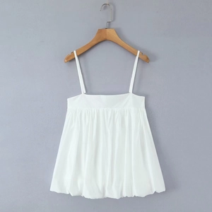 Detail of white pleated camisole top with thin straps and ruffled cotton texture