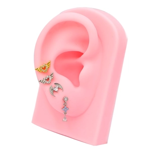 Détail de clous d'oreilles cœur en zircon et pendants sur un modèle d'oreille en silicone