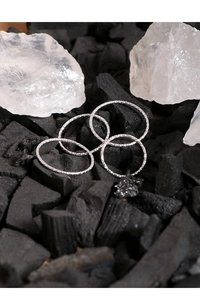 Detail of four 1mm S925 sterling silver rings with diamond texture on charcoal