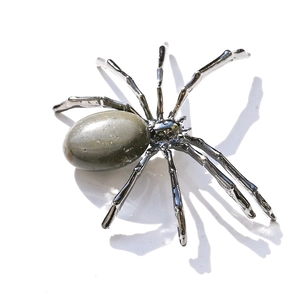 Macro detail of a spider sculpture with green peridot gemstone and silver metal legs