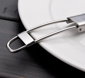 Macro shot of stainless steel folding spoon handle with wire design on white plate