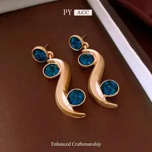Elegant gold S-shaped earrings set with round deep blue cubic zirconia gemstones