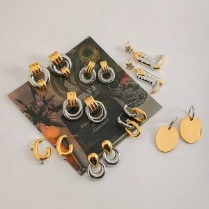 Détail de boucles d'oreilles bicolores avec breloques étoiles et textures métalliques