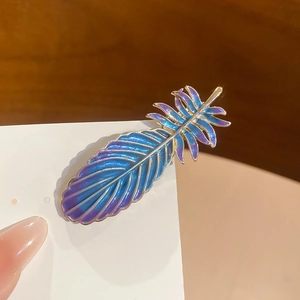 Vue détaillée de la barrette plume avec dégradé violet-bleu et bordure dorée chic