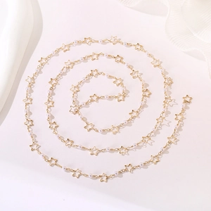 Detail of gold star necklace with small white pearls arranged in a spiral on white surface