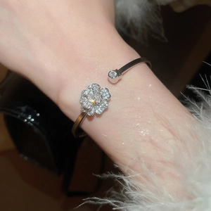 Dettaglio di un elegante bracciale rigido in argento con fiori in zircone e punta sferica