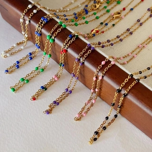 Detail of colorful enamel bead necklaces in gold titanium steel on a display stand