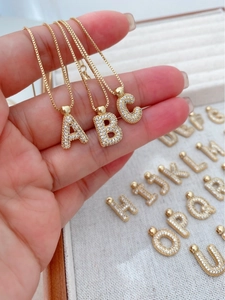 Macro view of gold-plated initial pendants with sparkling zircon inlays for necklaces