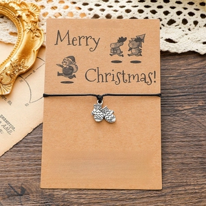 Detail of Christmas glove charm on black woven bracelet with vintage card packaging