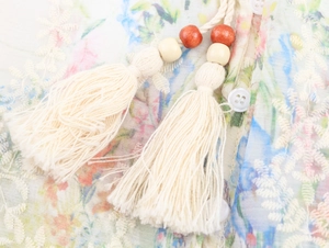 Détail de chemisier bohème avec broderie florale, pompons perlés et texture du tissu