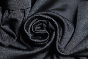 Detailed macro view showing the high-elastic black knitted fabric texture and soft drape