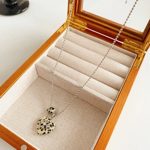 Detail of spotted heart pendant necklace with silver cross in a wooden jewelry box