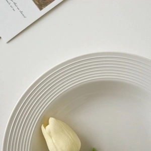 Minimalist white ceramic pasta plate featuring elegant ribbed edges and a glossy finish