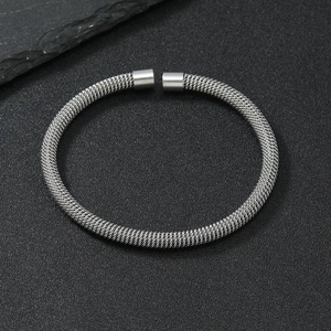 Industrial style silver mesh wire stainless steel cuff bangle on a dark textured background