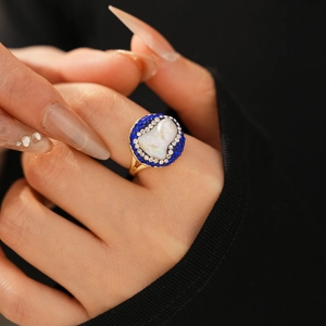 Detailed shot of a vintage gold-plated ring featuring faux pearl and blue crystal accents