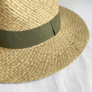 Detailed close-up of woven natural straw texture with an olive green grosgrain ribbon band