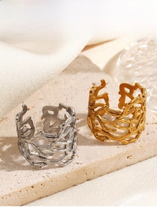 Dettaglio di anelli corallo in oro e argento su pietra beige e sfondo di seta fine