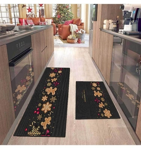 Detail view of two-piece black Christmas kitchen mats with gingerbread man and snowflake prints