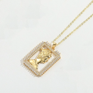 Macro detail of golden rectangular pendant with classical relief and clear zircon stones