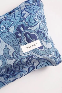 Macro detail of blue paisley jacquard fabric with silver threads and brand label
