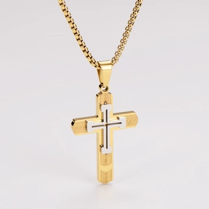Detailed view of dual-tone gold and silver cross pendant with intricate texture engraving