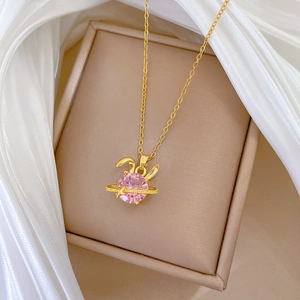 Macro detail of pink rabbit planet necklace with stars on a beige jewelry box