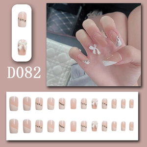 Detailed view of nude gradient press-on nails with 3D white bows and rhinestones (D082)