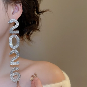 Macro shot of silver tassel earrings with sparkling 2026 number pendant on a model