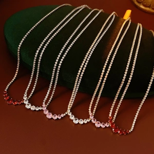Detail view of six zircon pendant necklaces in red, pink, and clear crystal on velvet