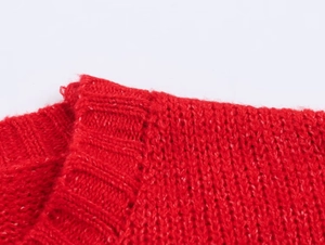 Macro shot of red knit sweater neckline showing thick cable texture and ribbed collar
