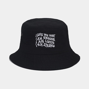 Detail of white embroidered inspirational quotes on a black cotton bucket hat with metal eyelets