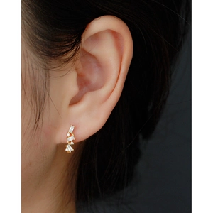 Close-up of gold geometric U-shaped hoop earrings with micro-pave cubic zirconia on ear